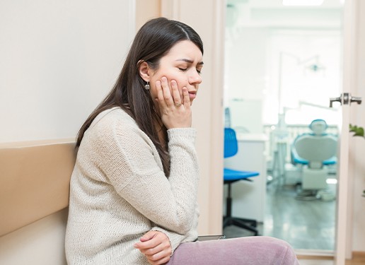 woman holding cheek in pain