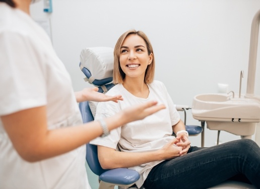 woman in white in exam chair smiling at dentist